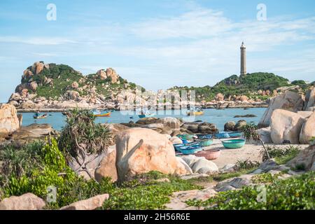 Vue panoramique sur le phare sur la belle rive avec de grandes pierres.Vue sur la baie avec de l'eau cristalline.Bateaux de pêche vietnamiens colorés. Banque D'Images