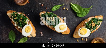 Sandwichs frits aux épinards, aux œufs et aux pignons ou à la bruschetta sur fond clair.Délicieux petit déjeuner sain ou en-cas.Vue de dessus. Banque D'Images