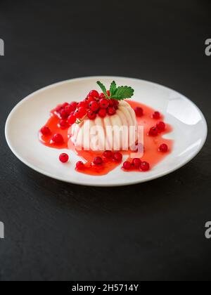 Gelée de noix de coco avec baies d'été.Panna cotta aux baies de cassis dans une assiette blanche. Banque D'Images