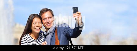 Heureux couple multiracial prenant photo selfie avec téléphone pendant les vacances de printemps.Europe vacances voyageurs voyageant dans la bannière de la ville panorama. Banque D'Images