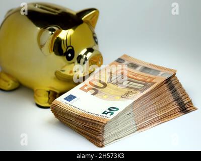 Golden piggy Bank avec pile de 50 billets en euros en premier plan. Banque D'Images