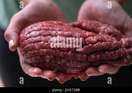 Les mains des femmes tiennent la viande hachée rouge, gros plan Banque D'Images