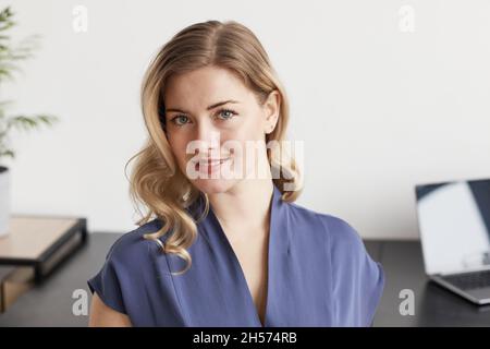 Portrait d'une femme d'affaires blonde confiante regardant l'appareil photo dans un minimum d'intérieur, espace de copie Banque D'Images
