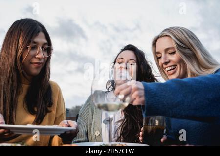 Des amis heureux mangeant et buvant du vin ensemble à l'extérieur dans le restaurant patio - concentrez-vous sur le visage de la fille centrale Banque D'Images