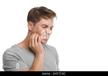 Un homme caucasien étricheur millennal découplé appuie sa main pour tricher et souffre de mal de dents Banque D'Images