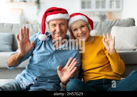 Un couple senior s'est réjouté de porter des chapeaux de père Noël en intérieur Banque D'Images