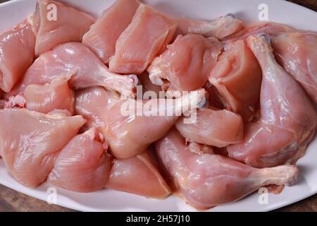 Poulet cru biriyani coupé sans peau disposé sur table blanche avec des ingrédients placés dans le fond avec le bois rustique fond. Banque D'Images