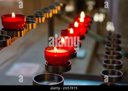 Bougies de prière rouges brûlantes à l'intérieur d'une église catholique sur un porte-bougie.Mise au point sélective. Banque D'Images