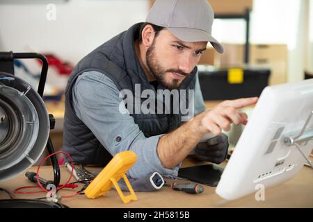 technicien mâle utilisant un voltmètre et un pc Banque D'Images