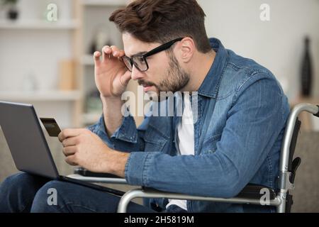 une personne handicapée détient une carte de crédit et utilise un pc Banque D'Images