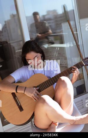 Un gros plan d'une jolie fille hispanique avec guitare, en riant dans le balcon, Argentine Banque D'Images