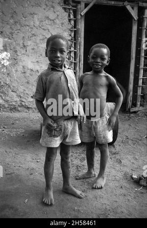 Afrique, Tanzanie, 1976.Le village d'Ujamaa Maasai les gens vivent encore dans leurs maisons traditionnelles.Deux petits garçons pauvres avec des estomacs étendus. Banque D'Images