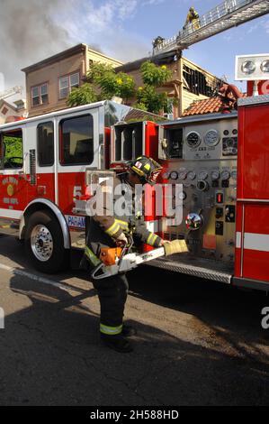 Un pompier de la ville de San Diego prépare une tronçonneuse lors d'un incendie de structure à San Diego, Californie, sur University Avenue Banque D'Images