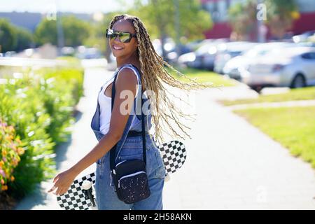 Jeune femme noire déplaçant ses tresses colorées dans le vent.Style africain typique. Banque D'Images