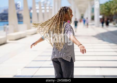 Jeune femme noire déplaçant ses tresses colorées dans le vent.Style africain typique. Banque D'Images