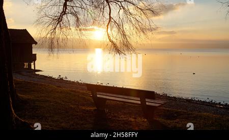 Un banc en bois près du lac Ammersee à Herrsching, Bavière au coucher du soleil un jour de décembre clair (Allemagne) Banque D'Images