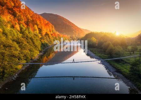 Vue aérienne de la silhouette de l'homme marchant sur le pont suspendu Banque D'Images