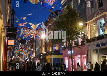 Londres, Royaume-Uni, 7 novembre 2021 : le dimanche après-midi, le West End de Londres regorge de clients qui profitent du temps sec pour faire du shopping.Les lumières de Noël au-dessus de Carnaby Street présentent des papillons multicolores, des présentoirs spéciaux sont dans les vitrines de magasin et parler de problèmes de chaîne d'approvisionnement signifie que les détaillants encouragent les gens à faire leurs achats de Noël tôt.Anna Watson/Alay Live News Banque D'Images