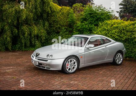 ALFA ROMEO GTV V6 24V Lusso stationné sur une route pavée avec des buissons derrière Banque D'Images