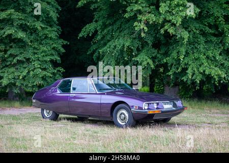 Violet Seventies Citroën SM garée sur l'herbe avec bois derrière Banque D'Images