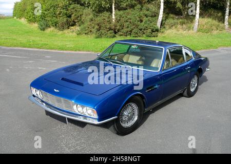 Aston Martin DBS voiture classique garée sur une voie de campagne avec des arbres derrière Banque D'Images