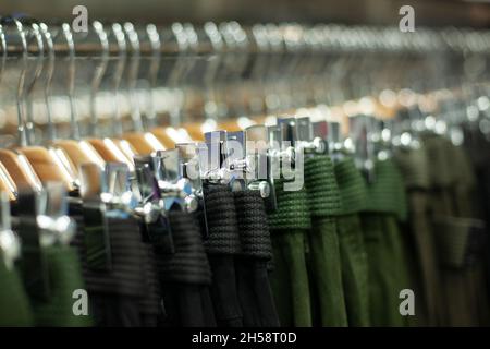 Pantalons en magasin sur cintres.Détails du magasin de vêtements.Placement de marchandises en tissu.Les cintres sont suspendus en rangée sur une barbell. Banque D'Images