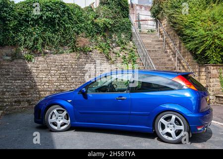 Ford Focus RS (2003) stationné dans une rue résidentielle urbaine étroite, sous un mur en pierre bancarisé Banque D'Images