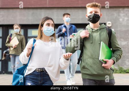 Adolescents dans les masques marchant après les leçons Banque D'Images