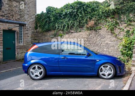 Ford Focus RS (2003) stationné dans une rue résidentielle urbaine étroite, sous un mur en pierre bancarisé Banque D'Images