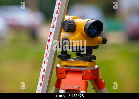 vue rapprochée d'un appareil de niveau géodésique bon marché avec une règle en tour à l'extérieur Banque D'Images