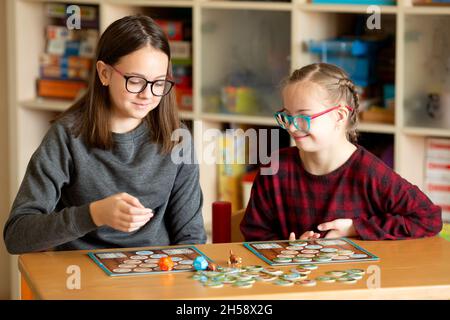 Fille avec le syndrome de Down joue à des jeux de société en quarantaine à la maison avec sa sœur Banque D'Images