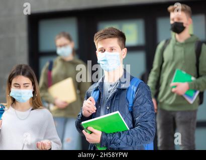 Adolescents dans les masques marchant après les leçons Banque D'Images