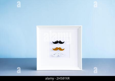 Moustaches mâles de différentes couleurs dans le cadre photo sur fond bleu.Le mois de la sensibilisation à la santé des hommes, le concept de masculinité du jour des pères.Diversité masculine Banque D'Images