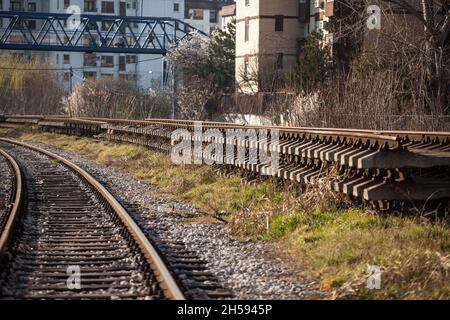 Photo d'une voie de chemin de fer avec un accent sur les nouveaux rails avec des traverses en béton, prêt à remplacer l'ancienne et l'infrastructure en ruines. Banque D'Images