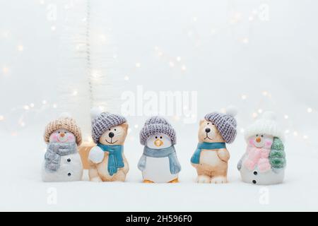 Figurines décoratives sur le thème de Noël.La statuette d'un chat, d'un pingouin, d'un ours et de deux bonhommes de neige dans un chapeau tricoté sur fond blanc.Fête déc Banque D'Images