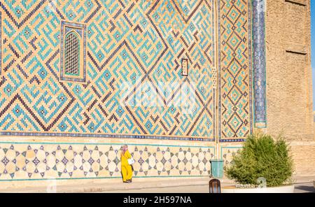 La femelle-croyant passe par le mur du mausolée de Khoja Ahmed Yasawi (14 siècle), le touchant.Principale attraction touristique au Turkestan, Kazakshtan Banque D'Images