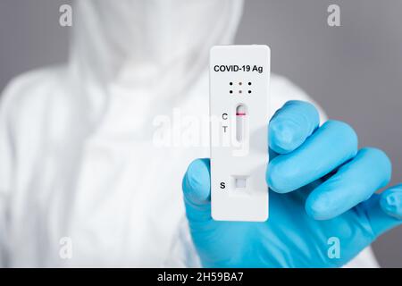 Médecin en costume d'EPI tenant le coronavirus (Covid-19) résultat de test négatif avec kit de test rapide Antigen (ATK) Banque D'Images