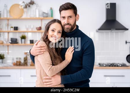 Épouse et mari amoureux se tenant à regarder l'appareil photo debout ensemble à la maison Banque D'Images