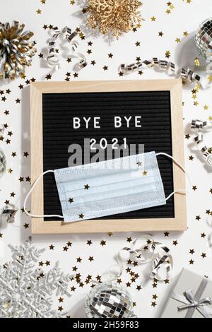 Tableau de lettres noir avec texte BYE BYE 2021 avec décoration et masque sur fond blanc.Le nouveau concept de l'oreille 2022 est heureux. Banque D'Images