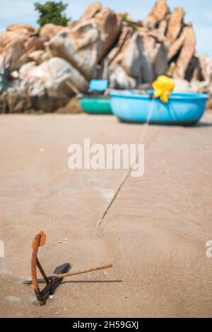 Un bateau de pêche rond est situé sur la plage pittoresque avec de grands rochers.Ancienne ancre rouillée.Photo de haute qualité Banque D'Images