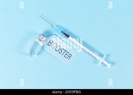 Concept pour la vaccination de rappel du virus Corina avec flacon et seringue sur fond bleu Banque D'Images