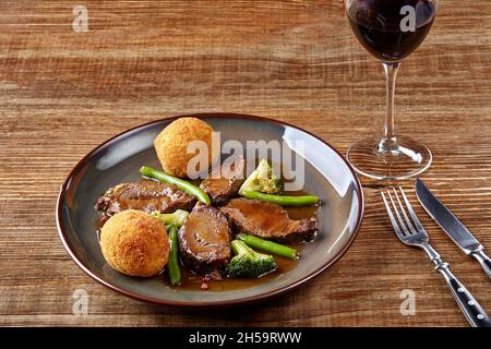 Joues de bœuf en sauce avec brocoli et haricots verts sur une assiette. Banque D'Images