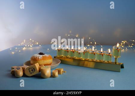 Vacances juives fond Hanukkah avec menorah- candélabre traditionnel, haut tournant et donut sur fond bleu Banque D'Images