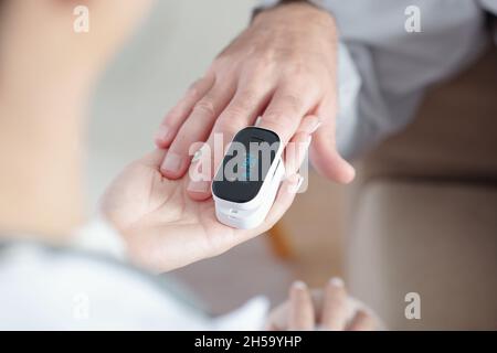 Médecin aidant le patient à mettre un oxymètre de pouls pour vérifier la saturation en oxygène Banque D'Images