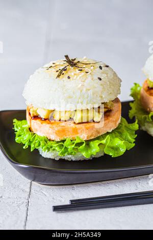 Hamburger de riz avec escalopes de saumon, sauce à l'avocat et au soja, fond gris. Banque D'Images