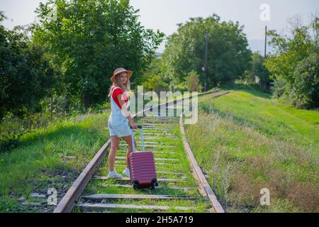 une petite fille voyage avec une valise le long des chemins Banque D'Images