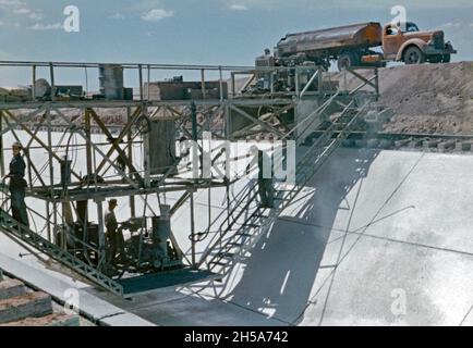 Travaux de construction sur le canal Wellton-Mohawk, près de Yuma, en Arizona, aux États-Unis, au début des années 1950.Ici, les ouvriers d'une plate-forme de forage sur rails se déplacent le long du béton fraîchement posé.Ils serrent la base et les parois inclinées de la voie navigable pour éviter que le matériau de revêtement ne se durcisse trop rapidement et ne se fissure.Le district d'irrigation et de drainage Wellton-Mohawk est situé dans le sud-ouest de l'Arizona, à l'est de Yuma, construit entre 1949 et 1957.Il permet l'irrigation dans la vallée inférieure de Gila avec de l'eau du fleuve Colorado via le canal de Gila jusqu'au canal Wellton-Mohawk, où il est pompé à environ 160 pieds jusqu'aux eaux de tête Banque D'Images