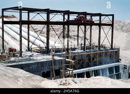 Travaux de construction sur le canal Wellton-Mohawk, près de Yuma, en Arizona, aux États-Unis, au début des années 1950.Ici, des travaux sont en cours sur l'une des stations de pompage le long du canal.Le squelette en acier est en place et les tuyaux en béton s'élèvent de l'arrière du pumphouse. Le district d'irrigation et de drainage Wellton-Mohawk est situé dans le sud-ouest de l'Arizona, à l'est de Yuma, construit entre 1949 et 1957.Il permet l'irrigation dans la vallée inférieure de Gila avec de l'eau du fleuve Colorado via le canal de Gila jusqu'au canal Wellton-Mohawk, où il est pompé à environ 160 pieds jusqu'aux eaux de tête – une photographie des années 1950. Banque D'Images