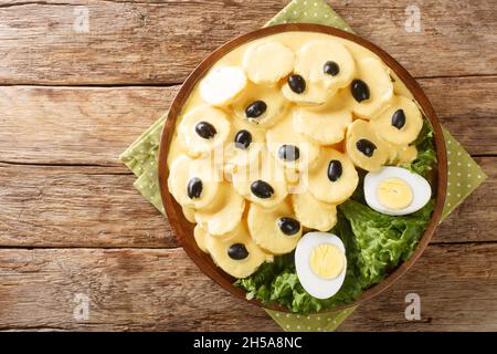 Papa a la Huancaina est un hors-d'œuvre composé de pommes de terre cuites en tranches qui sont étouffées dans une sauce veloutée épicée à proximité de l'assiette sur la table. Banque D'Images