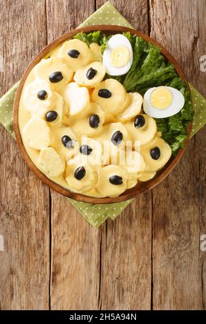 Papa a la Huancaina plat de pommes de terre en tranches avec une sauce spéciale gros plan dans l'assiette sur la table.Vue verticale du dessus Banque D'Images